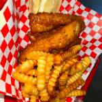 French fries, fried fish and a lemon atop a red and white checkered parchment from Captain's Galley