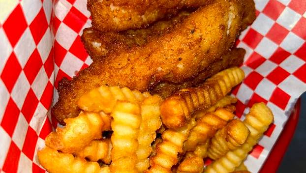 French fries, fried fish and a lemon atop a red and white checkered parchment from Captain's Galley