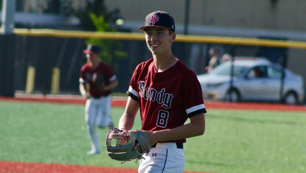 Sandy baseball player Brayden Sievertsen, wearing a red jersey, smiles on the baseball field