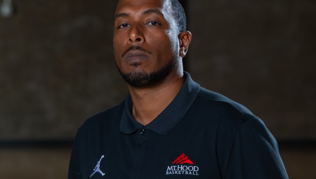Hany Doud stands with arms behind his back in the Mt. Hood Community College gym in a black polo shirt with the school logo in the top left corner