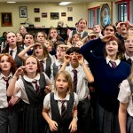 The Eastside Theater Company kid actors of Matilda the Musical stand in a group, wearing their gray school costumes