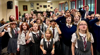 The Eastside Theater Company kid actors of Matilda the Musical stand in a group, wearing their gray school costumes