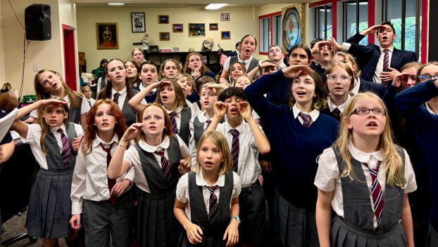 The Eastside Theater Company kid actors of Matilda the Musical stand in a group, wearing their gray school costumes
