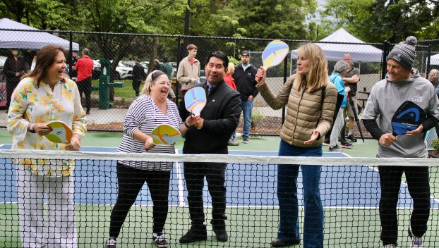 A group stands with pickleball paddles behind a net on the new blue courts built at Aspen Highlands Park