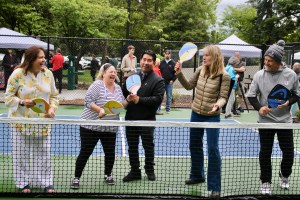 A group stands with pickleball paddles behind a net on the new blue courts built at Aspen Highlands Park