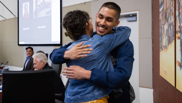 Reynolds junior Xavier Juarez hugs a Gresham City Councilor.