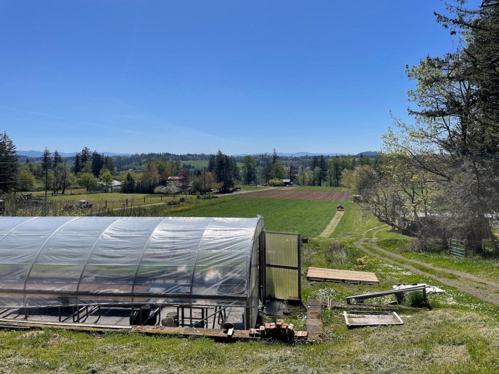 Crooked Tine Farm in Troutdale with a greenhouse and green farm fields stretching behind.